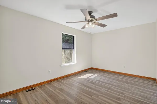 an empty room with wooden floor ceiling fan and windows