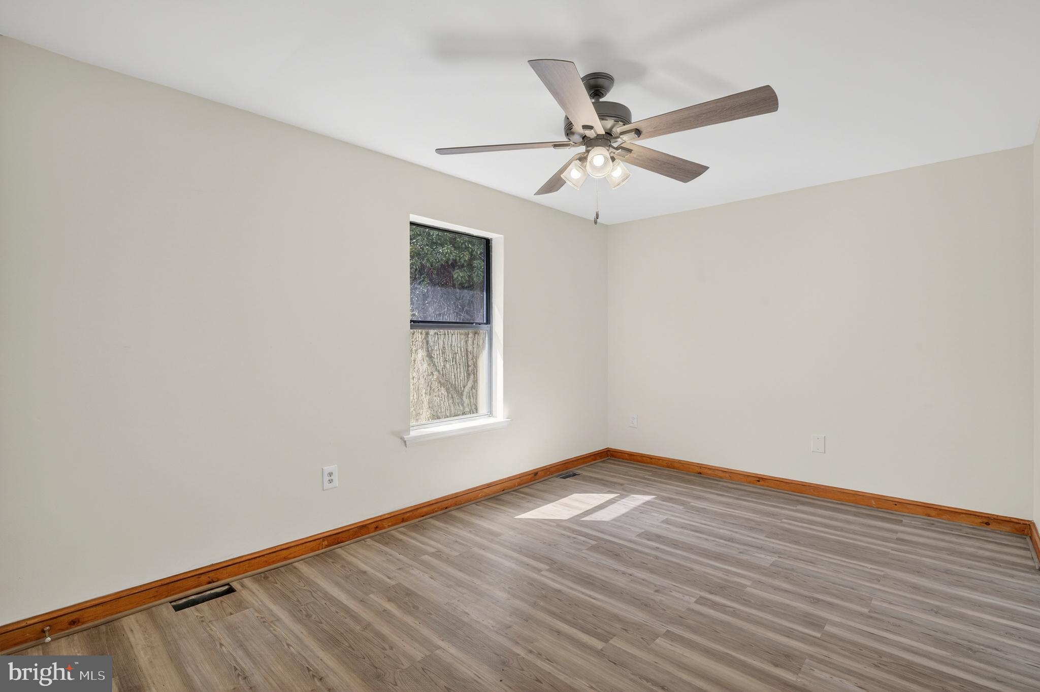 4037 1st Street Chesapeake Beach, MD 20732 - Photo 19 of 26 an empty room with wooden floor fan and windows
