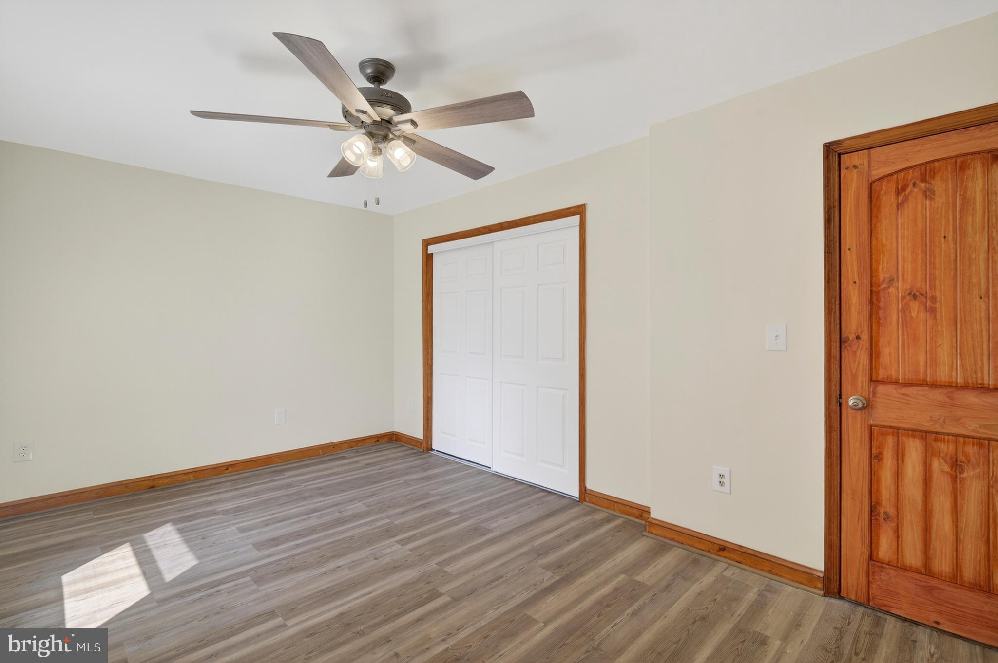 4037 1st Street Chesapeake Beach, MD 20732 - Photo 20 of 26 an empty room with wooden floor ceiling fan and windows