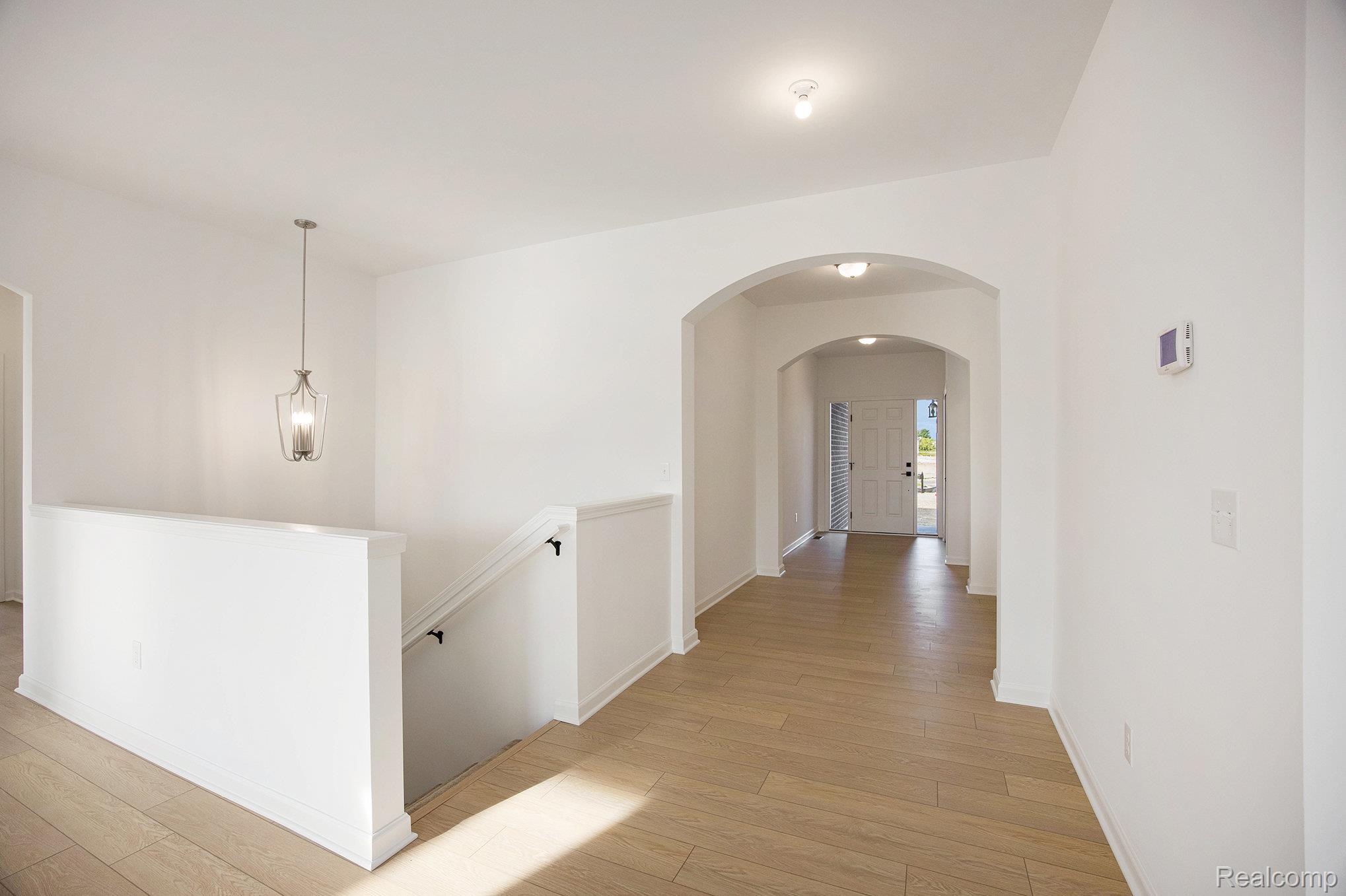 68788 Place Road New Haven, MI 48050 - Photo 16 of 29 Corridor with arched walkways, light wood-style flooring, and an upstairs landing