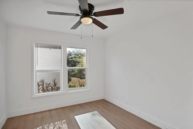 an empty room with wooden floor closet and fan