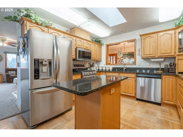 a kitchen with stainless steel appliances granite countertop a refrigerator a stove and a sink