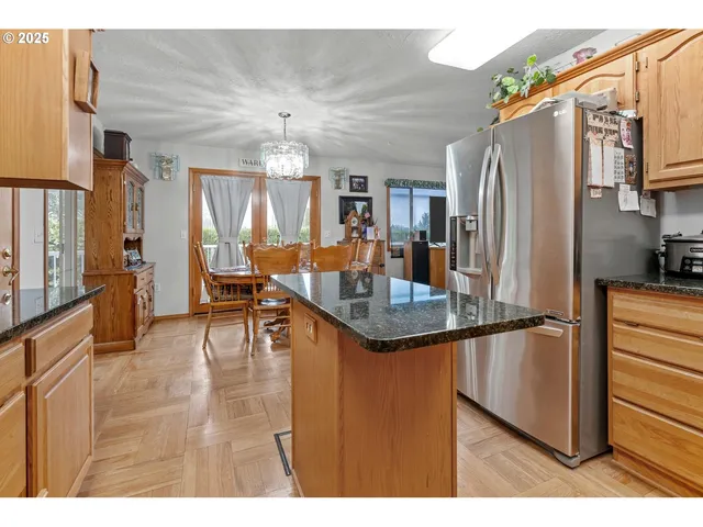 a kitchen with stainless steel appliances granite countertop a refrigerator a stove and a sink with wooden floor