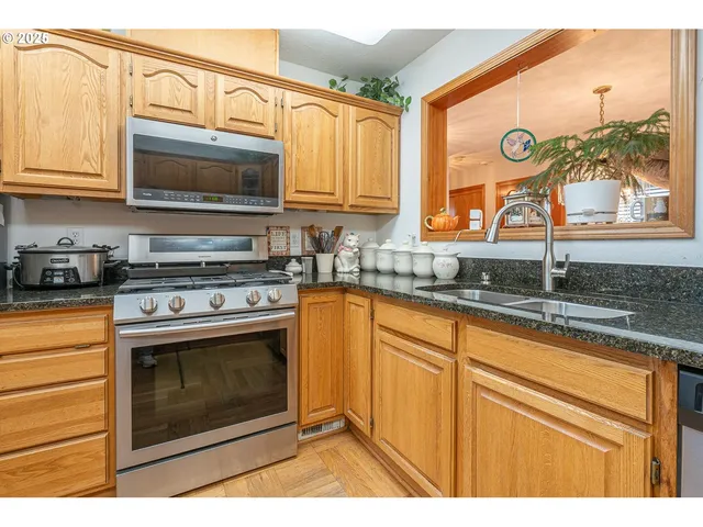 a kitchen with stainless steel appliances granite countertop a stove a sink and a microwave