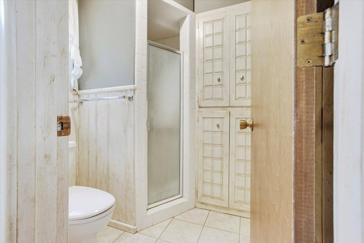 205 Smith Avenue New Home, TX 79381 - Photo 16 of 27 a bathroom with a granite countertop shower and a toilet