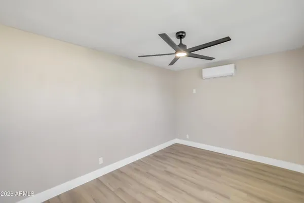 a view of empty room with wooden floor and fan