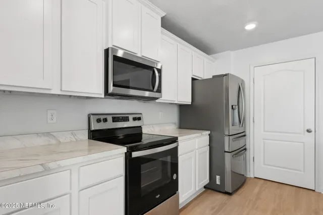 a kitchen with stainless steel appliances white cabinets white stove a microwave and a refrigerator
