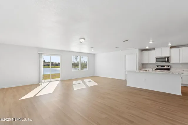 a view of an empty room with kitchen appliances and a window