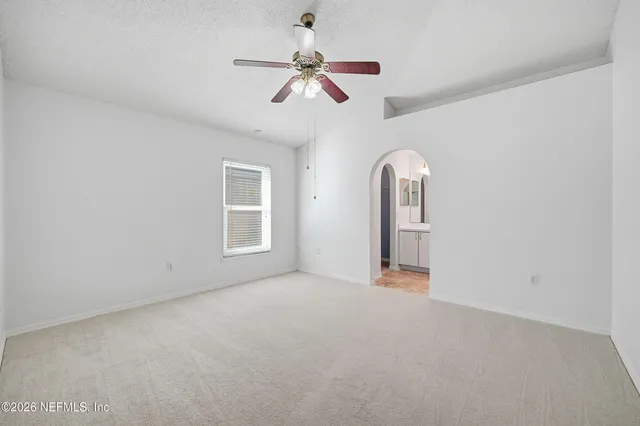 an empty room with chandelier fan and windows