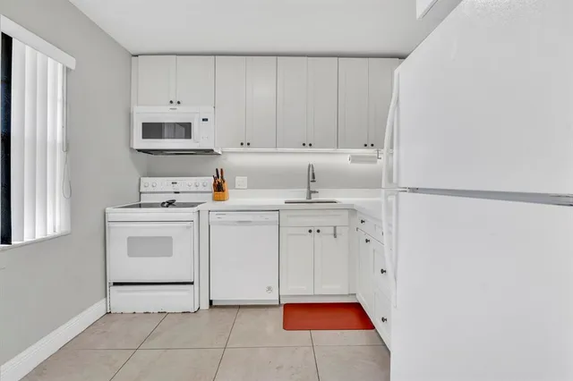 a kitchen with white cabinets and white appliances