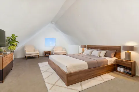 a spacious bedroom with a bed a table and a potted plant