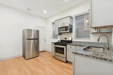 a kitchen with stainless steel appliances granite countertop a refrigerator sink and stove