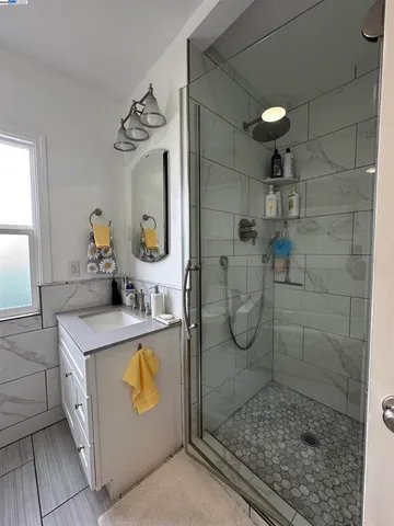 a bathroom with a granite countertop shower a mirror and vanity