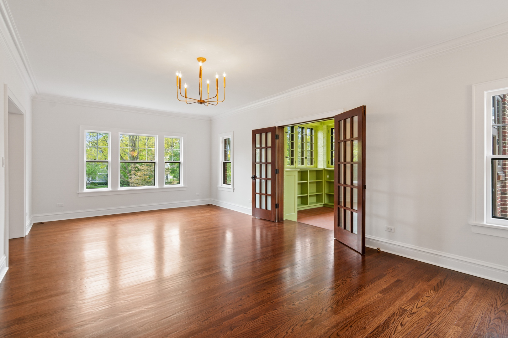 1045 Pine Street Winnetka, IL 60093 - Photo 7 of 38 an empty room with wooden floor chandelier and windows