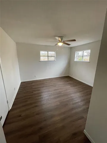 an empty room with wooden floor chandelier fan and windows