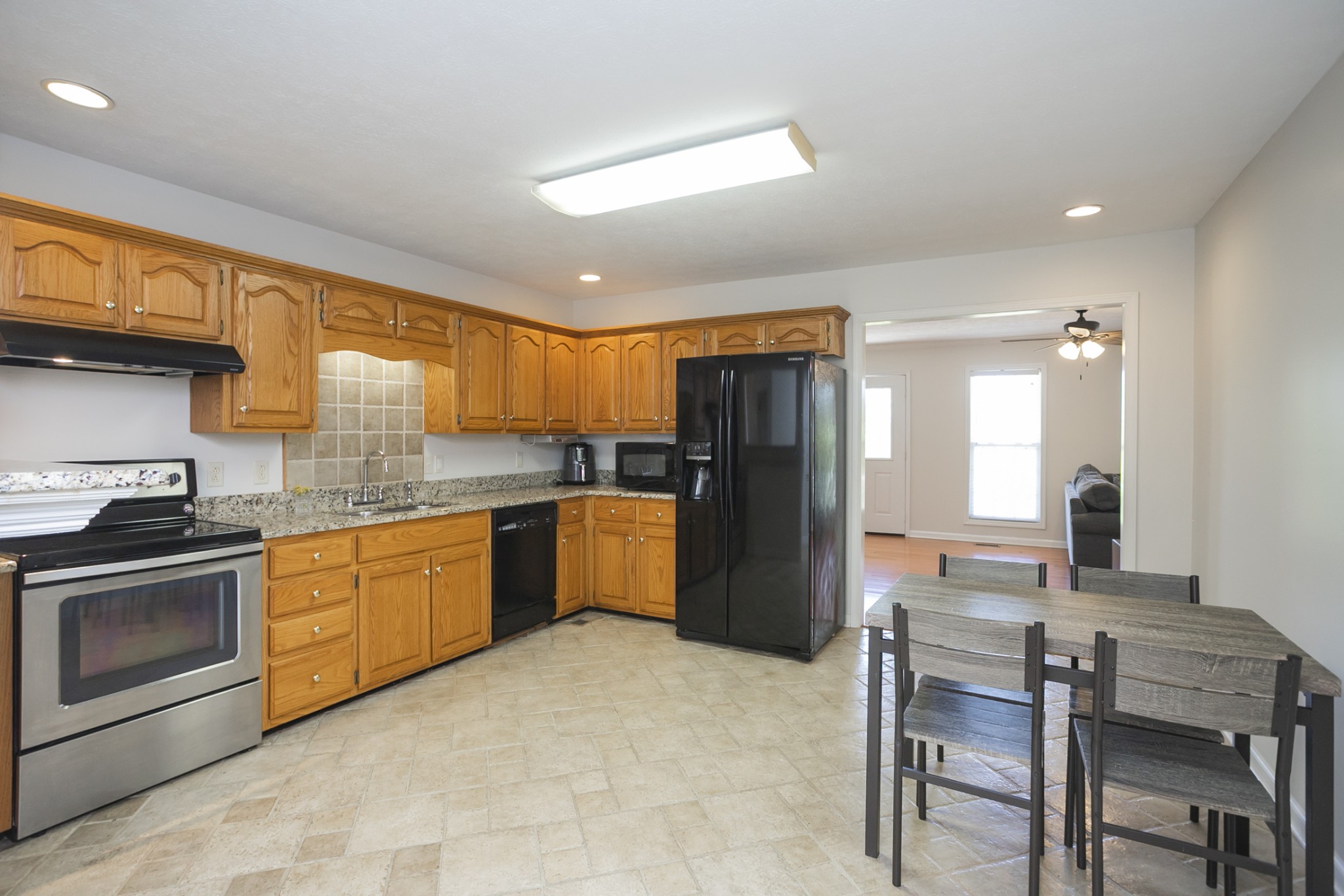 3354 Lipscomb Cemetery Road Springfield, TN 37172 - Photo 9 of 46 a kitchen with stainless steel appliances granite countertop a refrigerator a stove a sink a dining table and chairs with wooden floor