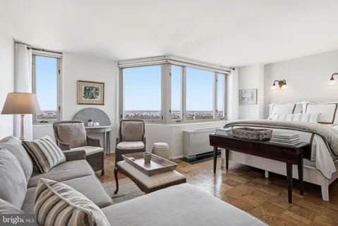 a living room with furniture a large window and a lamp