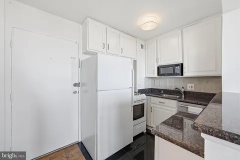 a white refrigerator freezer sitting inside of a kitchen with stainless steel appliances wooden floor