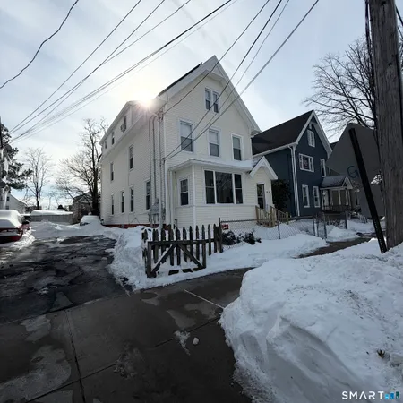 a view of a white house with a yard covered in snow