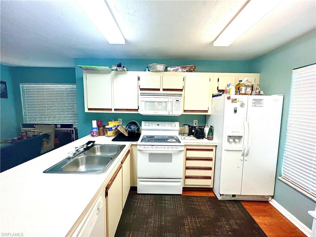 2207 San Marco Road, Unit 4104 Marco Island, FL 34145 - Photo 7 of 21 a kitchen with a white stove refrigerator and white cabinets with wooden floor