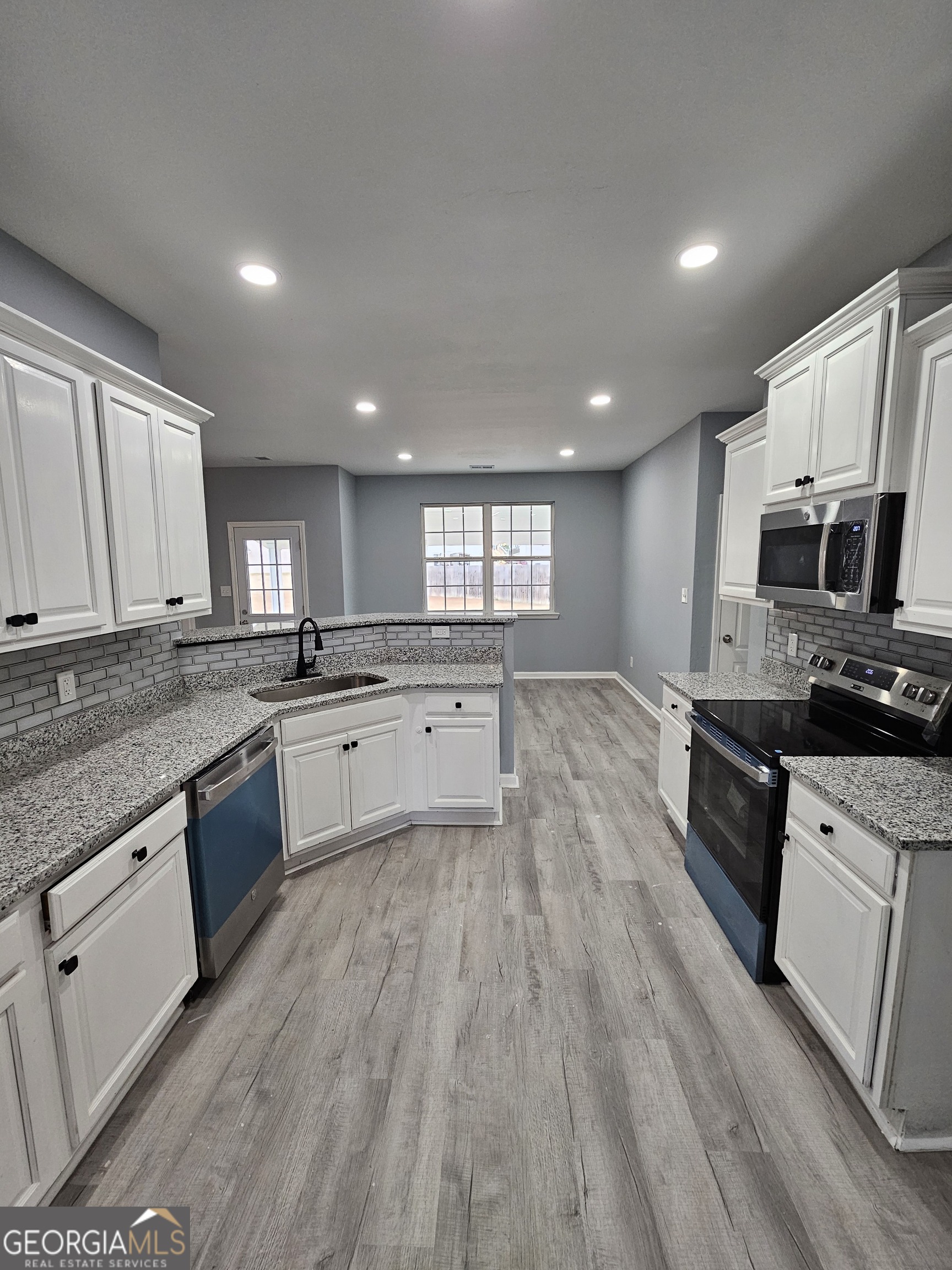 248 Sky Hawk Lane Macon, GA 31216 - Photo 5 of 6 a large kitchen with granite countertop a stove top oven a sink dishwasher a dining table and chairs with wooden floor