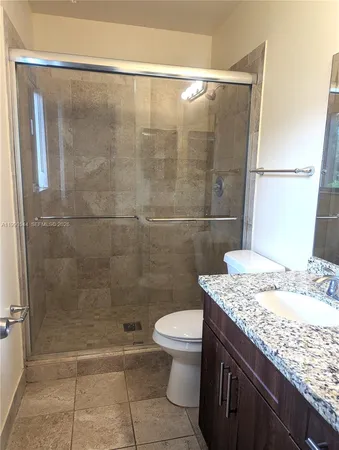 a bathroom with a granite countertop sink a toilet and shower