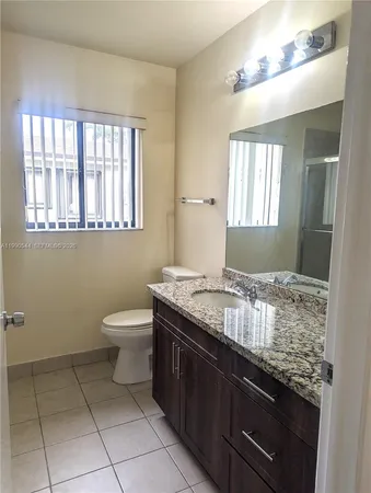 a room with a granite countertop sink a toilet and window