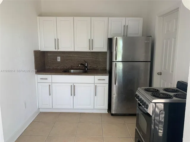 a kitchen with white cabinets and refrigerator