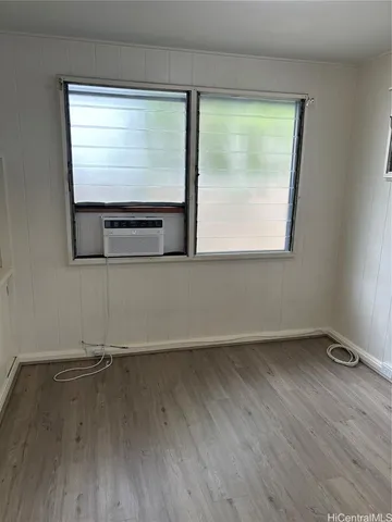 a view of empty room with wooden floor and window