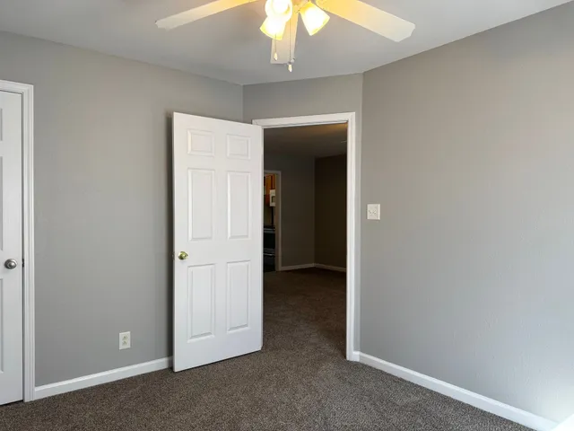 an empty room with a ceiling fan and entryway