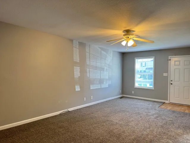an empty room with windows and chandelier fan