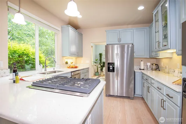 a kitchen with stainless steel appliances granite countertop a stove a refrigerator a sink and dishwasher with wooden floor