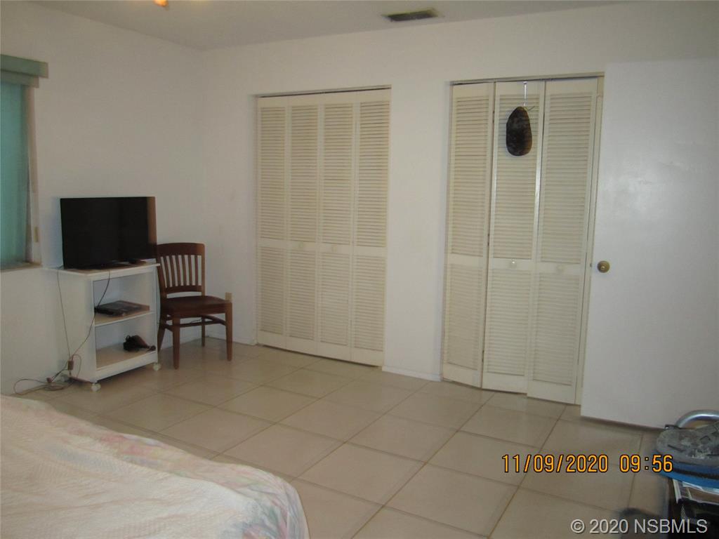 511 Cardinal Drive Edgewater, FL 32141 - Photo 9 of 13 a spacious bedroom with a bed and a chair