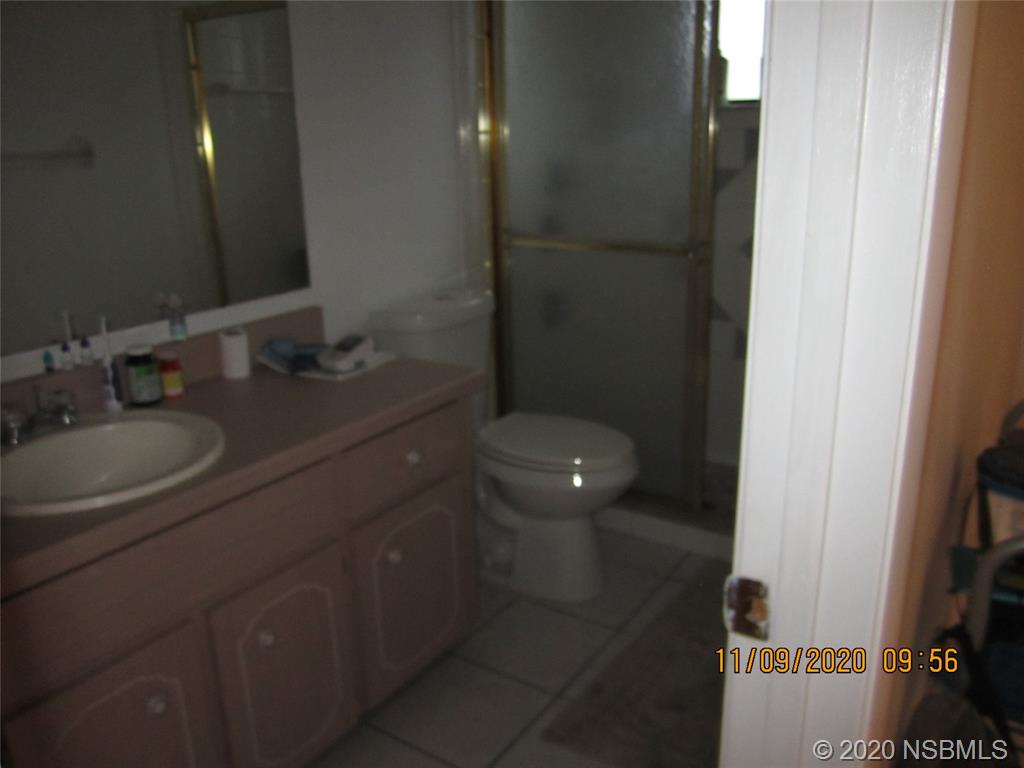 511 Cardinal Drive Edgewater, FL 32141 - Photo 10 of 13 a bathroom with a granite countertop sink a toilet and a mirror
