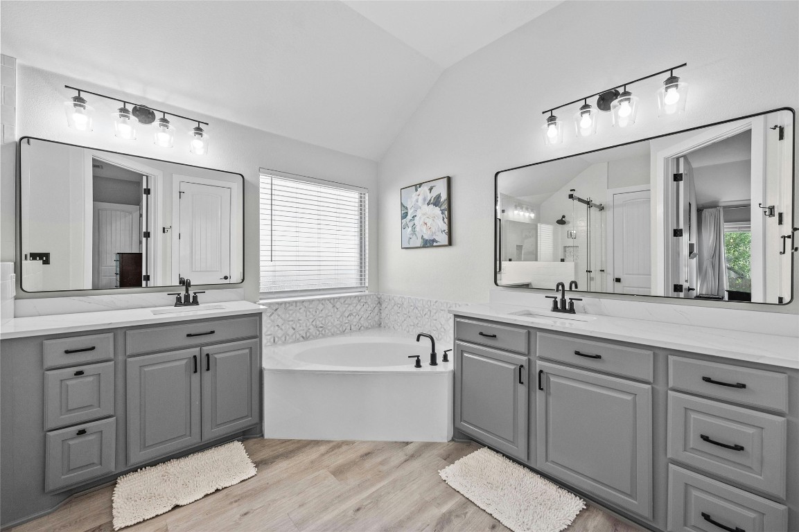 a spacious bathroom with a granite countertop double vanity sink a mirror and a bathtub