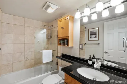 a bathroom with a sink double vanity a toilet a mirror and shower