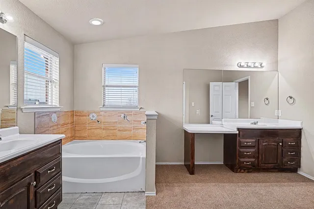 a bathroom with a tub a double vanity sink a mirror a and a window