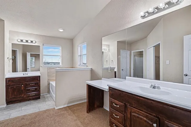 a bathroom with a granite countertop double vanity sink a mirror and a bathtub