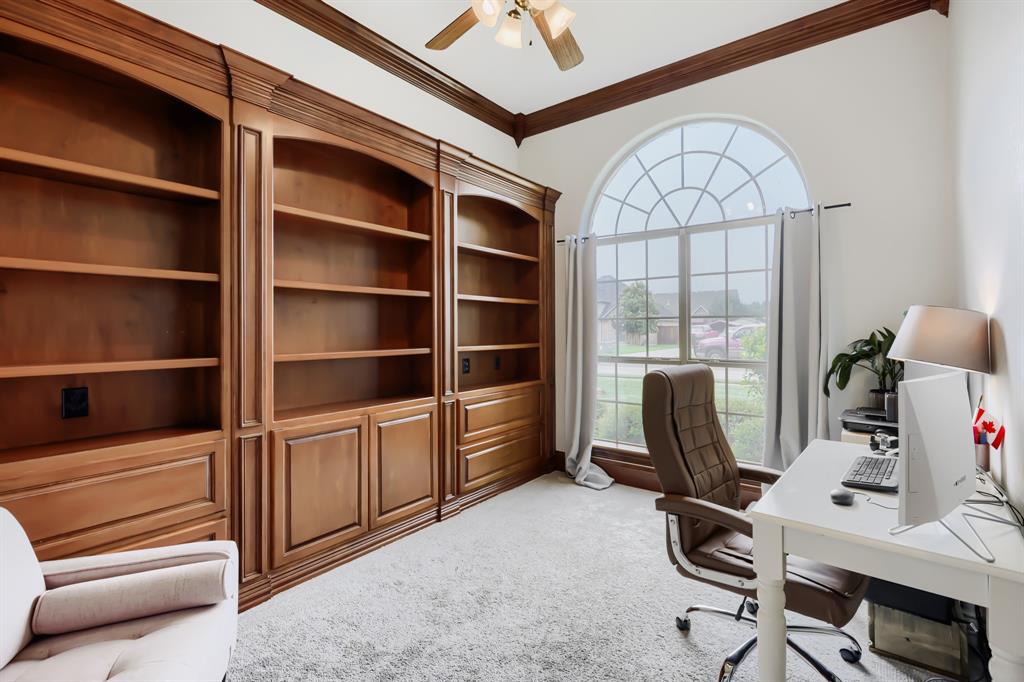 603 Ash Street Pilot Point, TX 76258 - Photo 11 of 28 Spacious room featuring extensive built-in wooden shelving and cabinetry, a large arched window, crown molding, and a ceiling fan