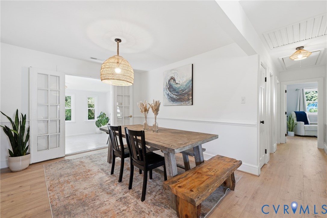 1100 Hollins Road Henrico, VA 23229 - Photo 17 of 38 a dining room with wooden floor a chandelier a wooden table and chairs