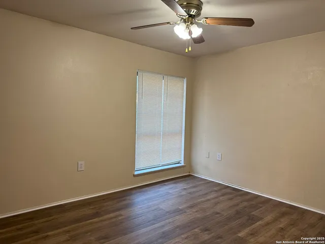 an empty room with wooden floor fan and windows
