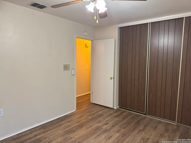 an empty room with wooden floor closet and entryway