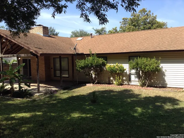a backyard of a house with table and chairs and potted plants