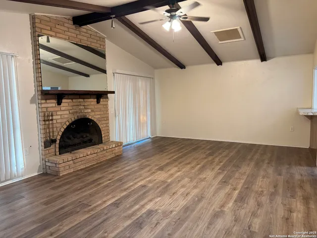 a view of empty room with fireplace and wooden floor