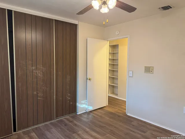 an empty room with wooden floor closet and windows