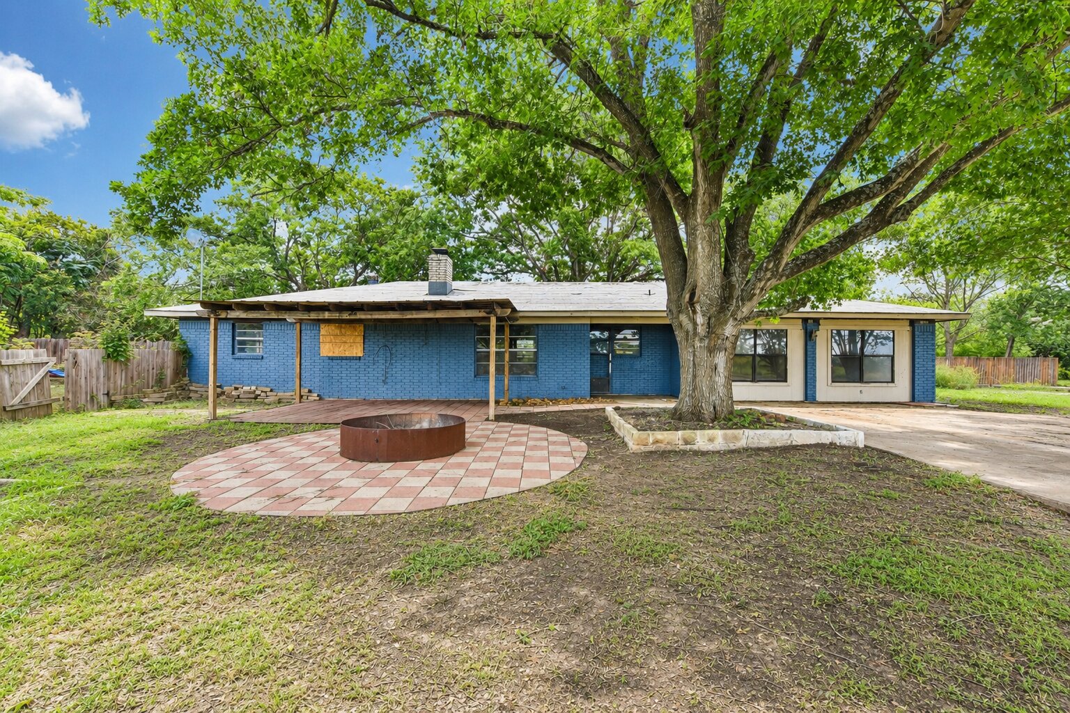 Mature trees shade this charming residence, offering a serene outdoor oasis with a ready-to-enjoy fire pit.