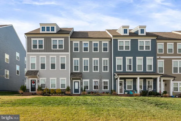 a front view of a building with garden and tall buildings