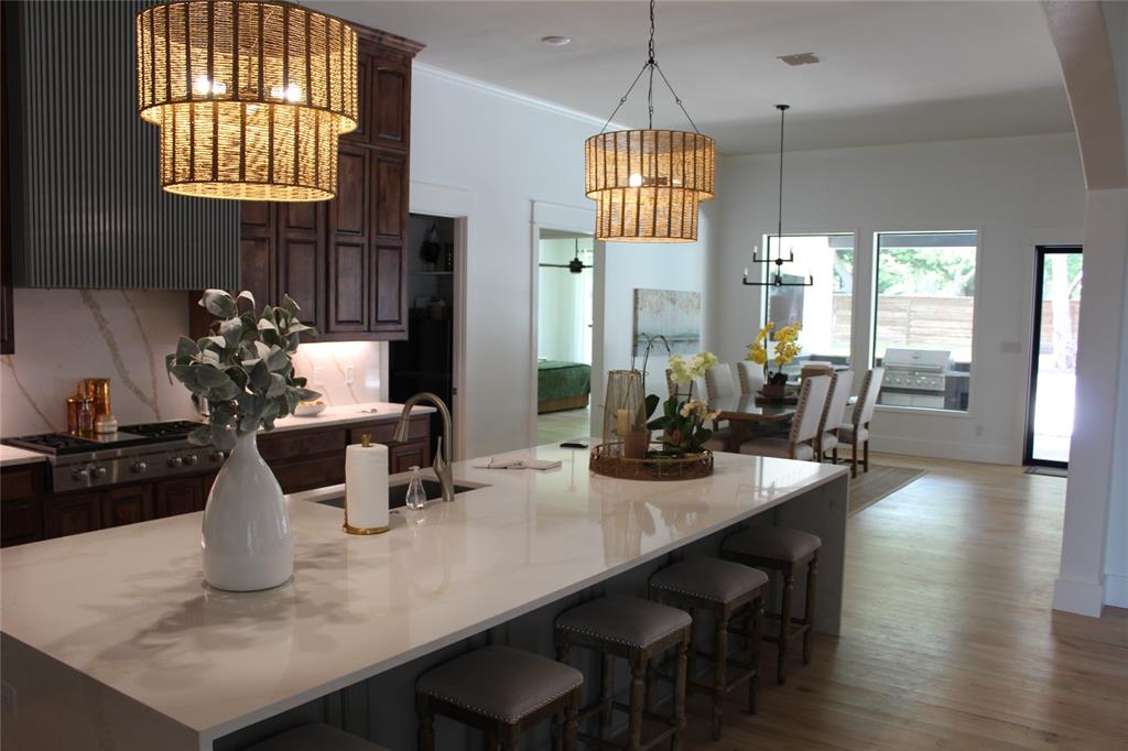 333 Renaissance Lane Heath, TX 75032 - Photo 17 of 35 Kitchen island with a light-toned countertop, a stainless steel sink with a gooseneck faucet, and seating for four