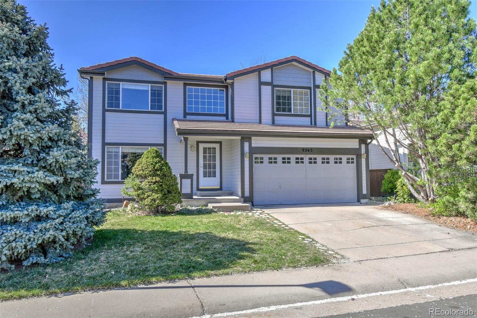 9265 Roadrunner Street Highlands Ranch, CO 80129 - Photo 2 of 28 a front view of a house with a yard and garage