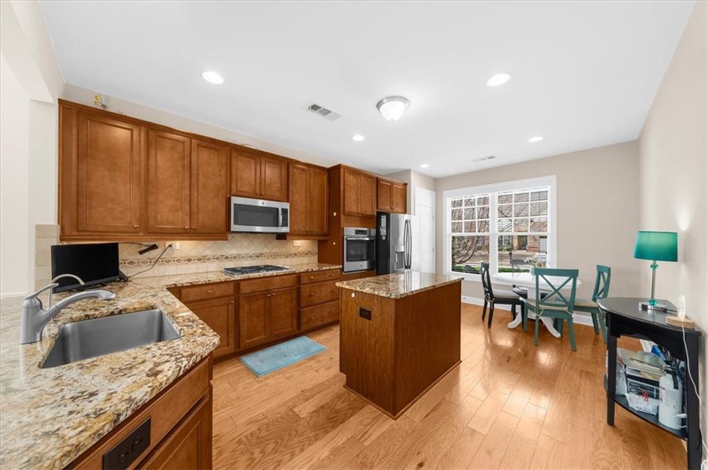 3739 Golden Leaf Point Southwest Gainesville, GA 30504 - Photo 15 of 60 a kitchen with stainless steel appliances granite countertop a stove top oven a sink dishwasher a dining table and chairs with wooden floor